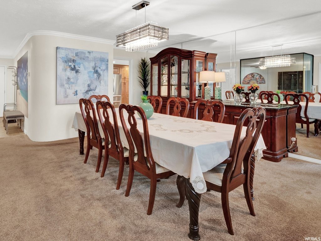 Dining room featuring light carpet, an inviting chandelier, and ornamental molding