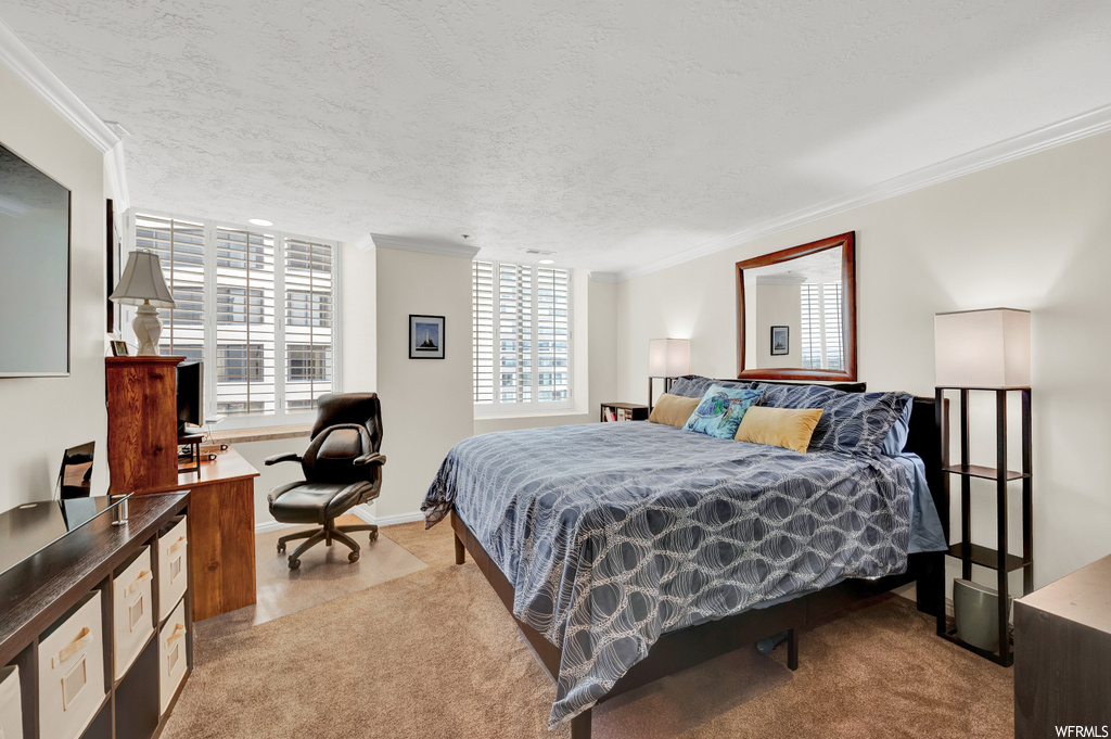 Bedroom featuring light colored carpet, a textured ceiling, and ornamental molding