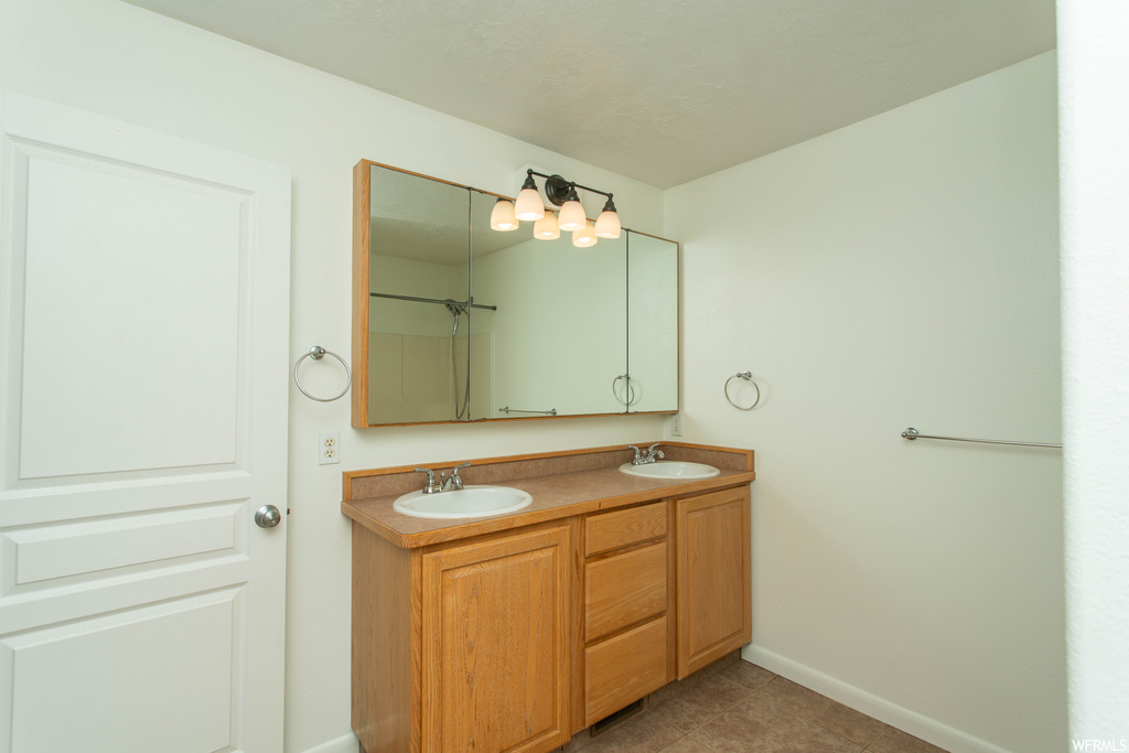 Bathroom featuring tile flooring, double sink vanity, and mirror