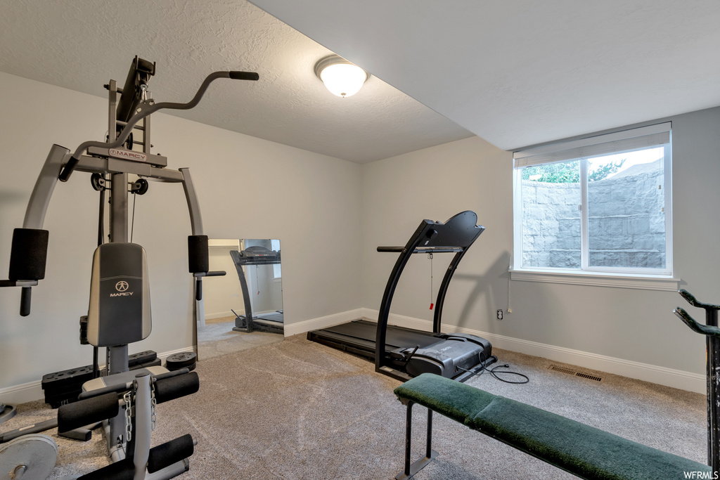 Workout room with light carpet and a textured ceiling
