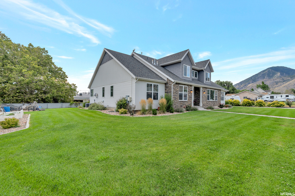 View of front of house with a mountain view and a front lawn