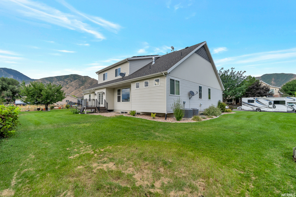 Rear view of house with a mountain view and a yard