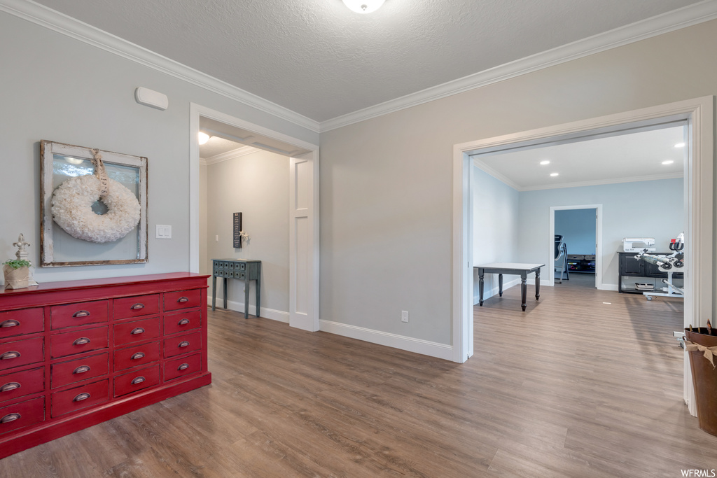 Interior space with light hardwood floors, crown molding, and a textured ceiling