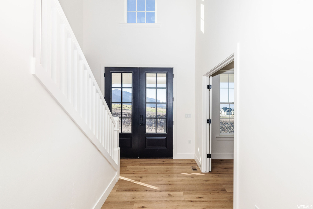 Foyer featuring french doors, a high ceiling, and light hardwood flooring