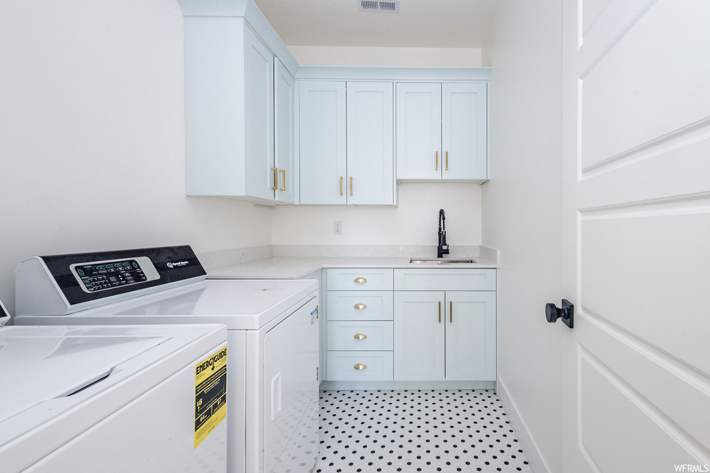 Washroom with sink, light tile flooring, separate washer and dryer, and cabinets