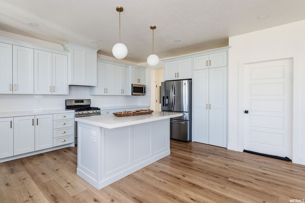 Kitchen featuring decorative light fixtures, white cabinetry, and light hardwood flooring