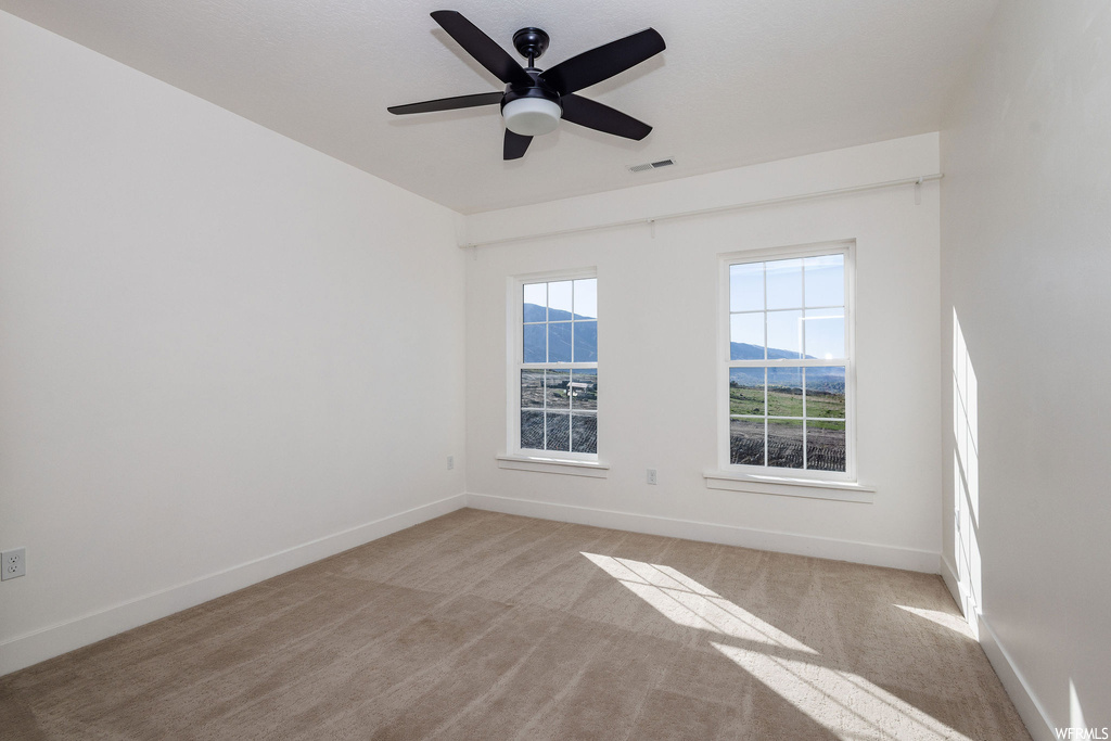 Carpeted empty room with a mountain view and ceiling fan