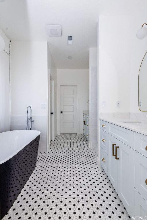 Bathroom featuring vanity, tile walls, a washtub, and tile flooring