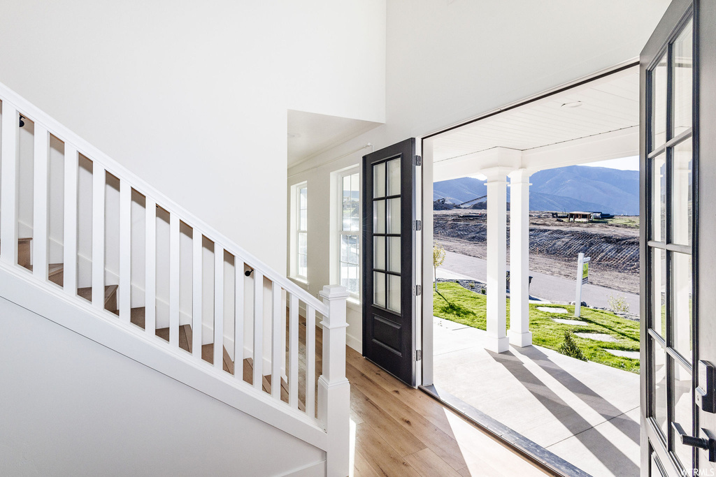 Entrance foyer with a mountain view, a towering ceiling, decorative columns, and light hardwood flooring