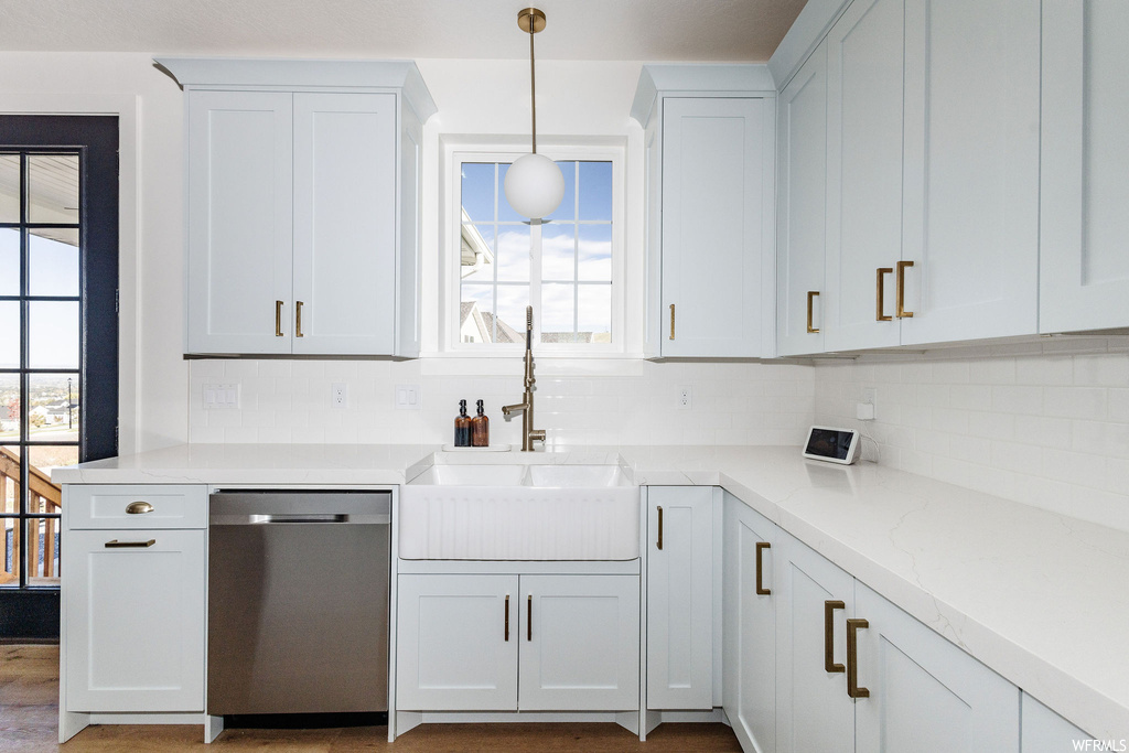 Kitchen with white cabinetry, backsplash, dishwasher, and decorative light fixtures