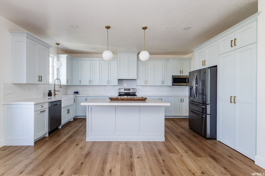 Kitchen featuring white cabinetry, light hardwood flooring, and appliances with stainless steel finishes