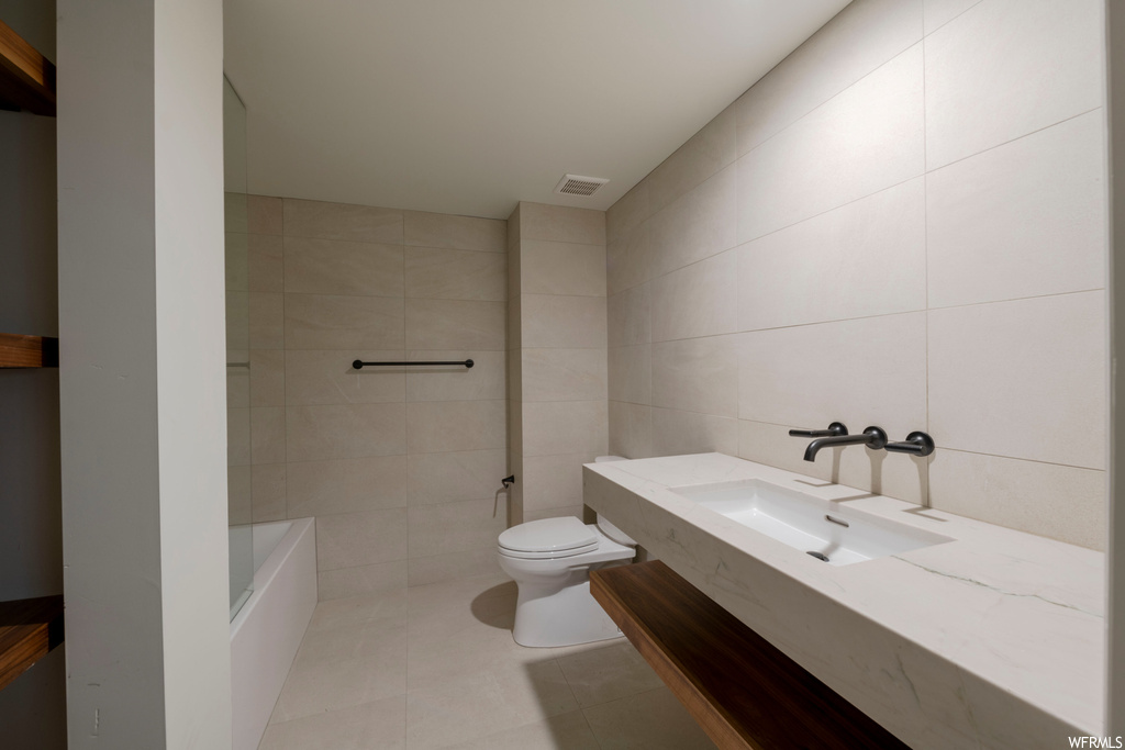 Full bathroom featuring bathing tub / shower combination, tile walls, vanity, and light tile floors