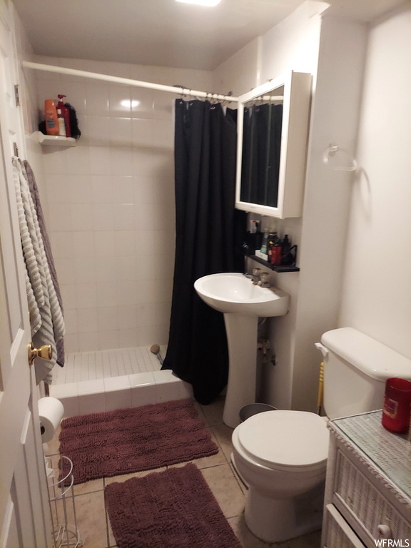 Bathroom featuring walk in shower, sink, tile flooring, and toilet