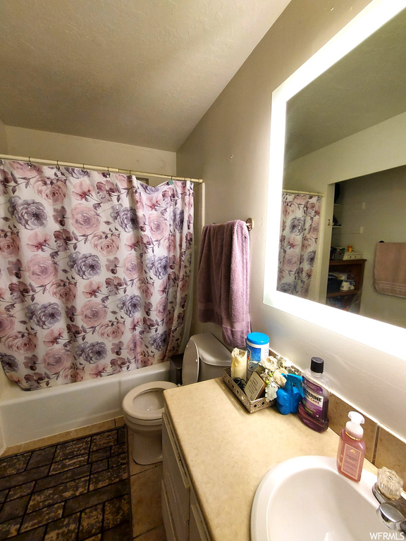 Full bathroom with toilet, oversized vanity, shower / tub combo, and tile flooring