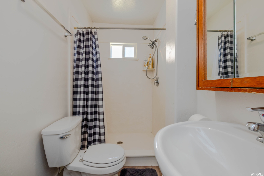 Bathroom with a shower with shower curtain, sink, mirror, and light tile flooring