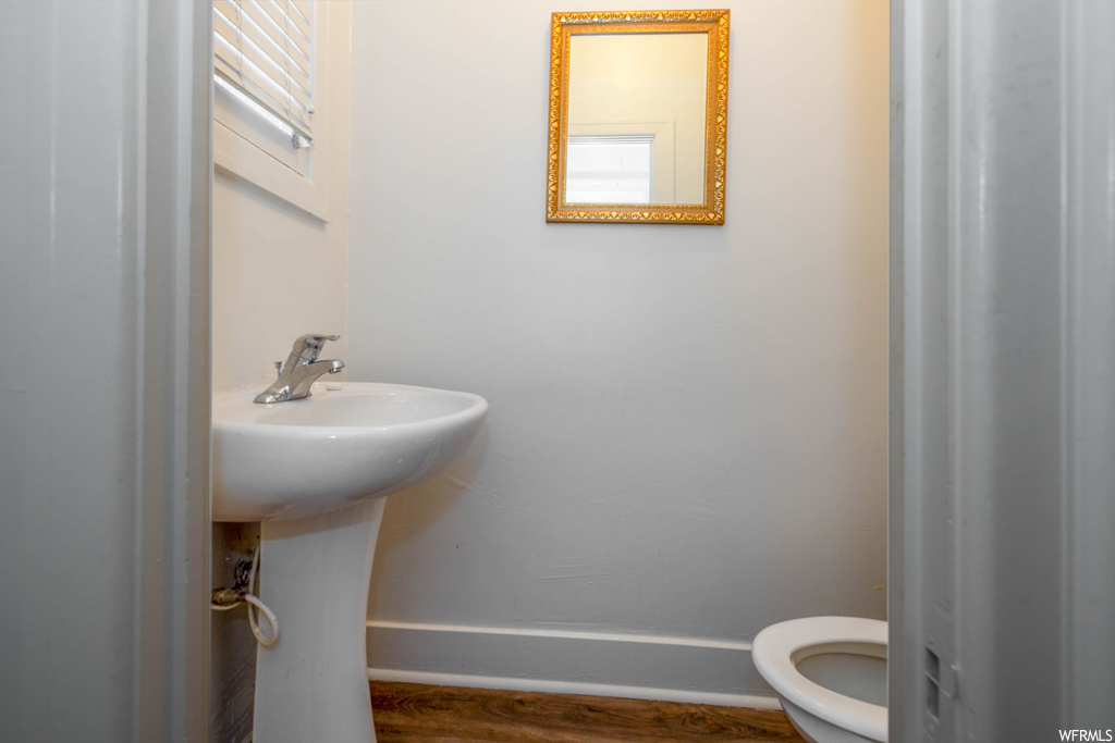 Bathroom featuring dark hardwood floors, mirror, and washbasin