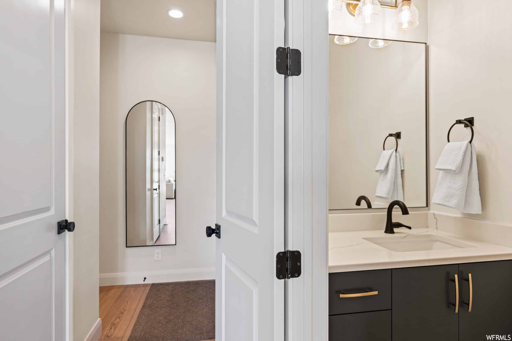 Bathroom with light hardwood floors, mirror, and vanity