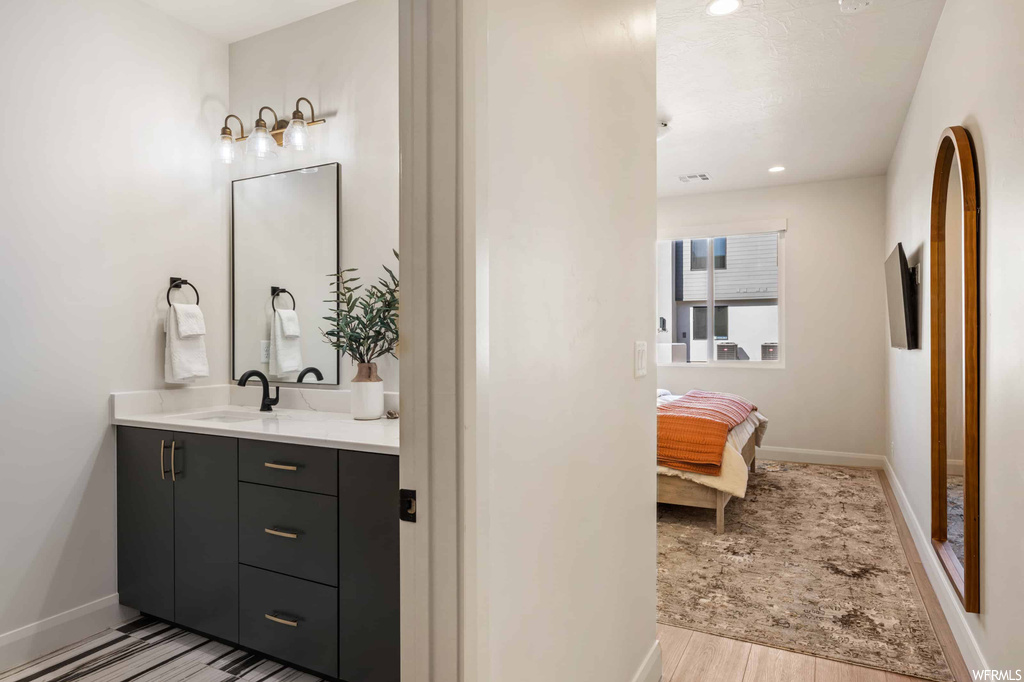 Bathroom with vanity, mirror, and light hardwood floors