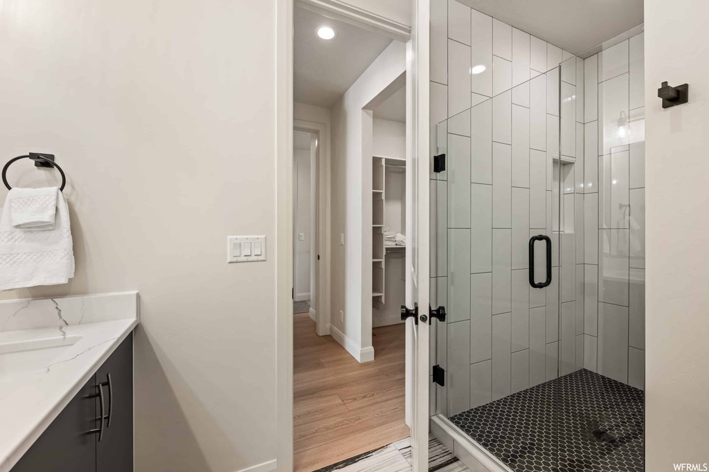Bathroom featuring an enclosed shower, vanity, and light hardwood flooring
