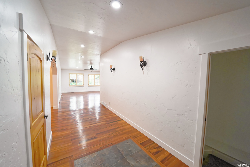 Corridor featuring vaulted ceiling and hardwood / wood-style flooring