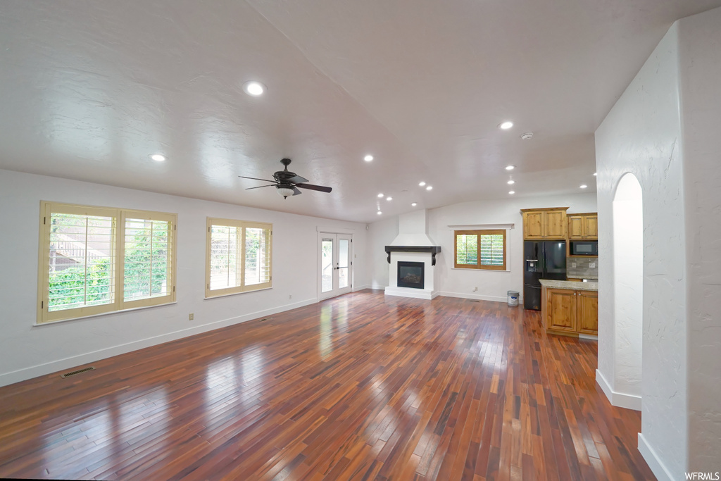 Unfurnished living room featuring dark hardwood / wood-style floors, ceiling fan, and vaulted ceiling