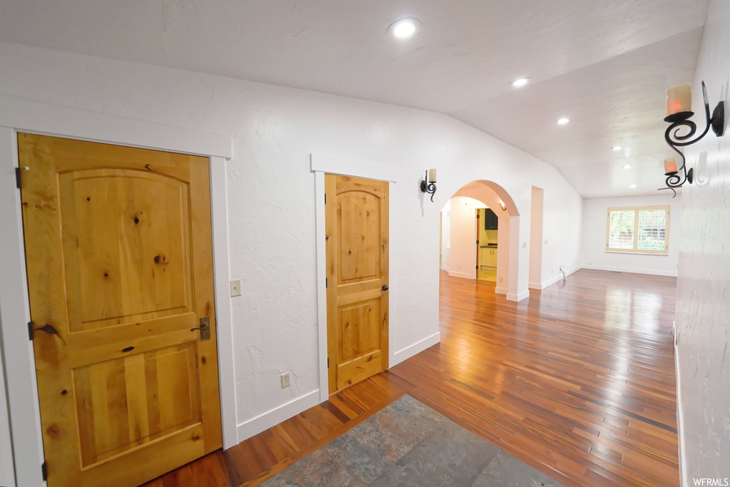 Hall with lofted ceiling and light hardwood / wood-style flooring