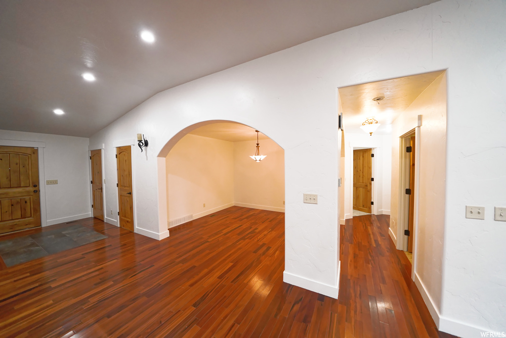 Spare room featuring dark hardwood / wood-style flooring and vaulted ceiling