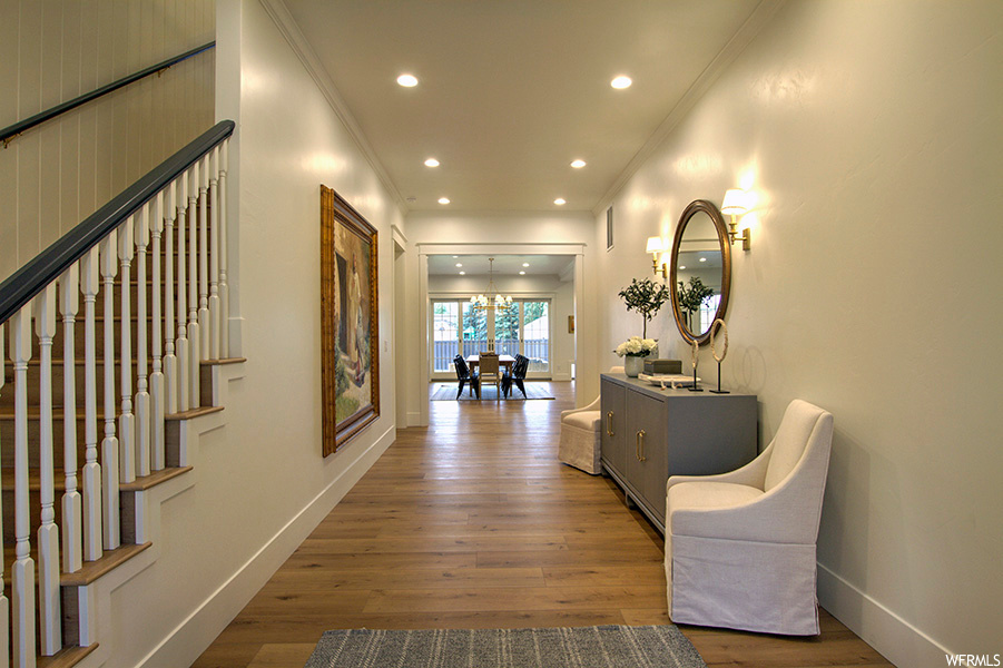 Hallway with ornamental molding and light hardwood floors