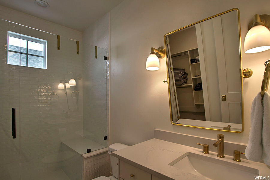Bathroom featuring vanity, mirror, and a shower with door