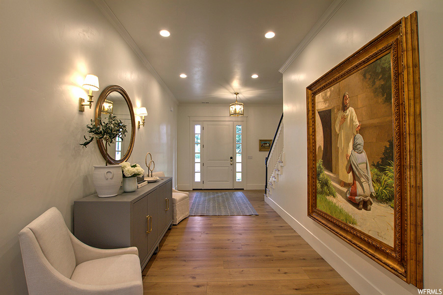 Entryway with ornamental molding and light hardwood floors