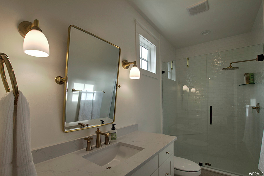 Bathroom featuring vanity, mirror, and a shower with door