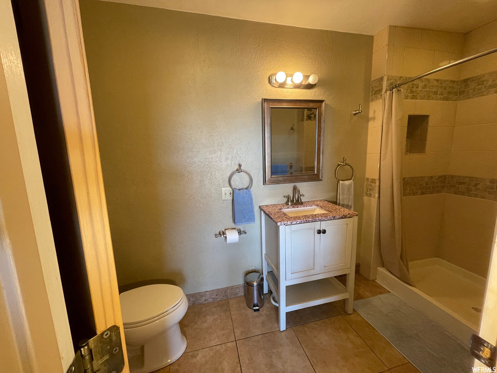 Bathroom with mirror, a shower with shower curtain, large vanity, and light tile floors