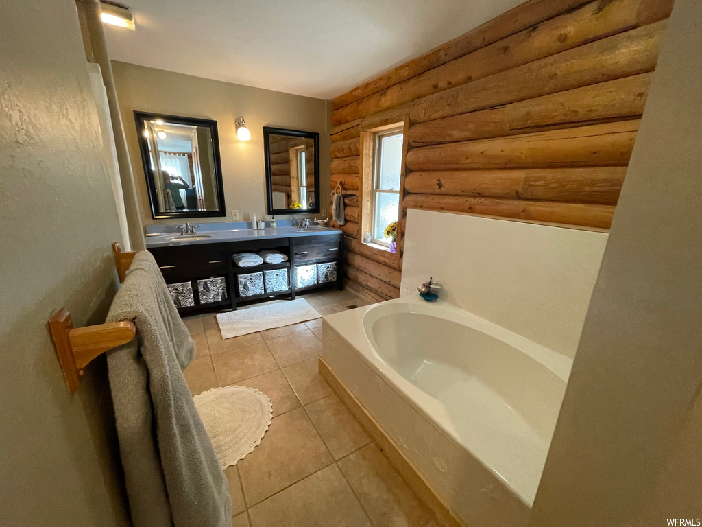 Bathroom with a tub, mirror, log walls, light tile floors, and dual vanity