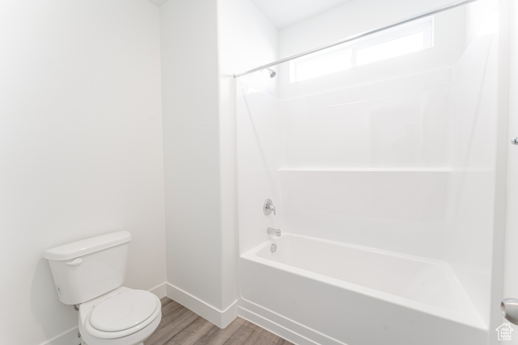 Bathroom with washtub / shower combination, toilet, and hardwood / wood-style floors