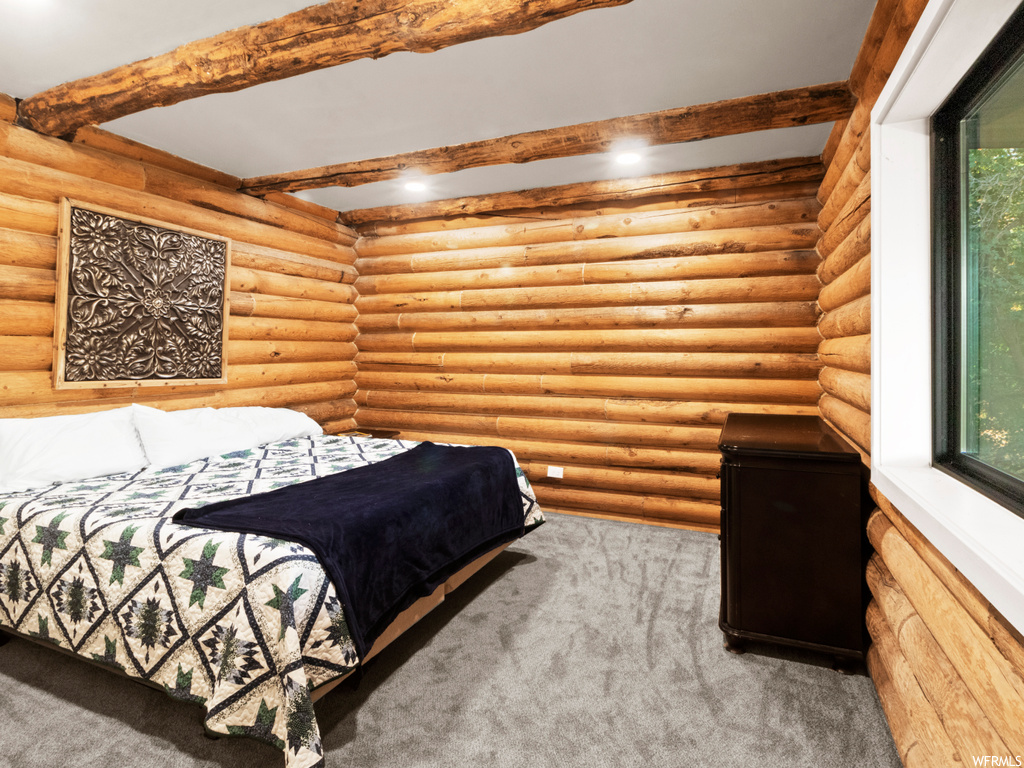Carpeted bedroom featuring log walls and beam ceiling