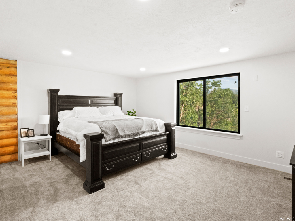 Bedroom featuring log walls and light carpet