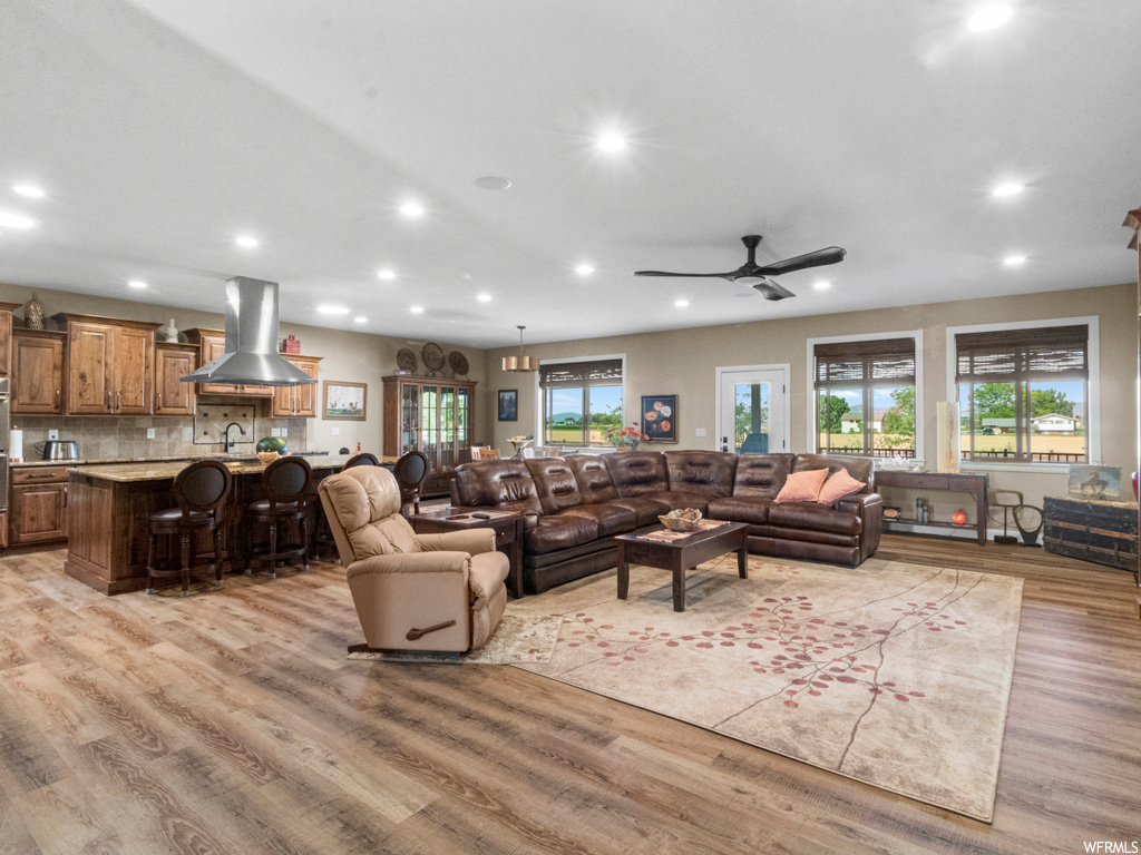 Living room with plenty of natural light, light hardwood floors, and ceiling fan
