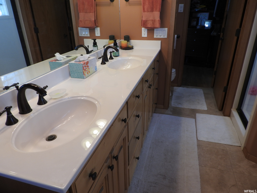 Bathroom with dark tile floors, dual vanity, and mirror