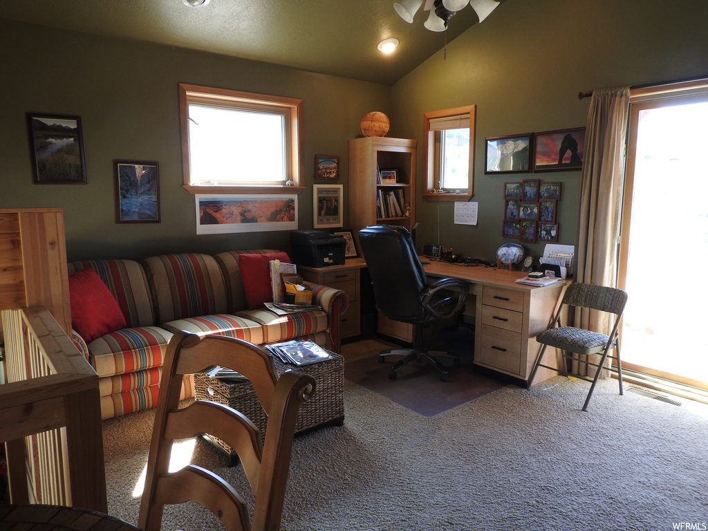 Carpeted home office with lofted ceiling