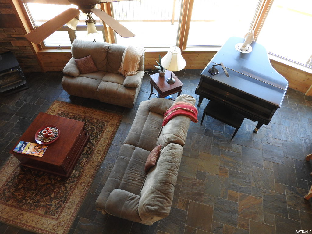 Living room featuring dark tile flooring, plenty of natural light, and ceiling fan
