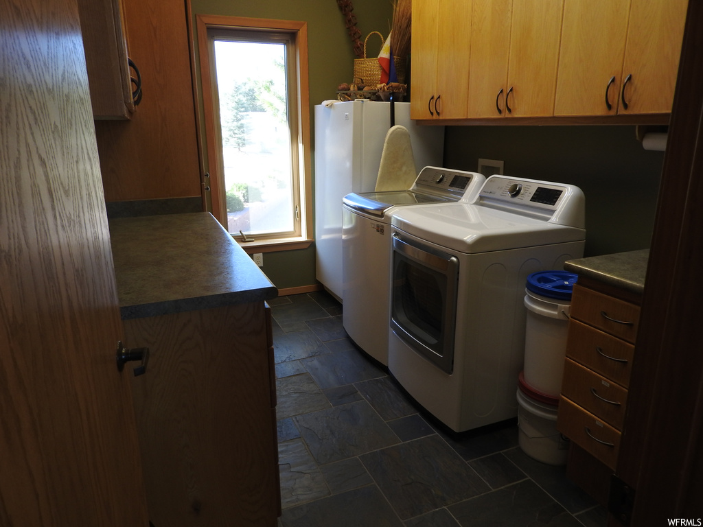Laundry room with dark tile floors and washer and dryer