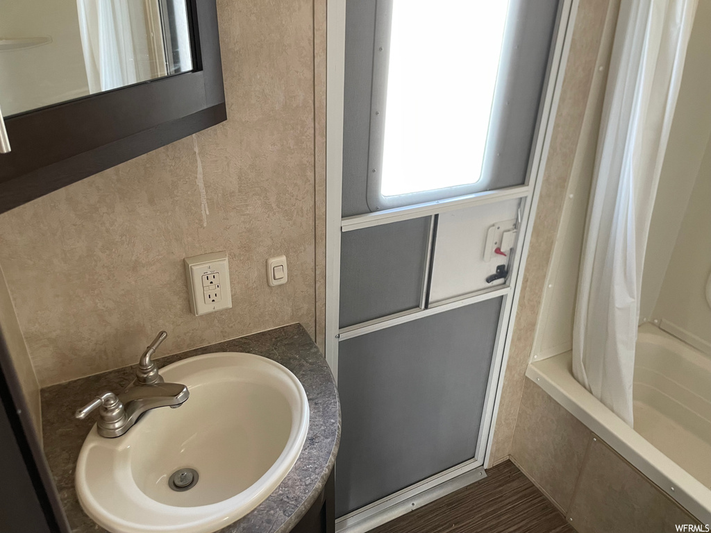 Bathroom with shower / bath combo with shower curtain, mirror, and washbasin
