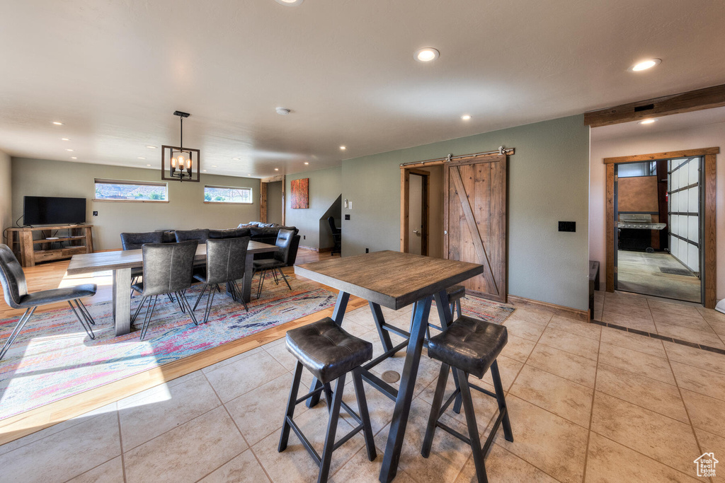 Dining area featuring a notable chandelier, light tile patterned flooring, and a barn door