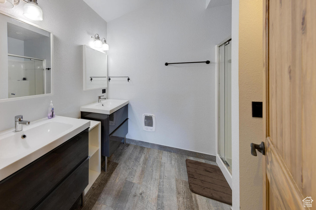 Bathroom with walk in shower, vanity, heating unit, and hardwood / wood-style flooring