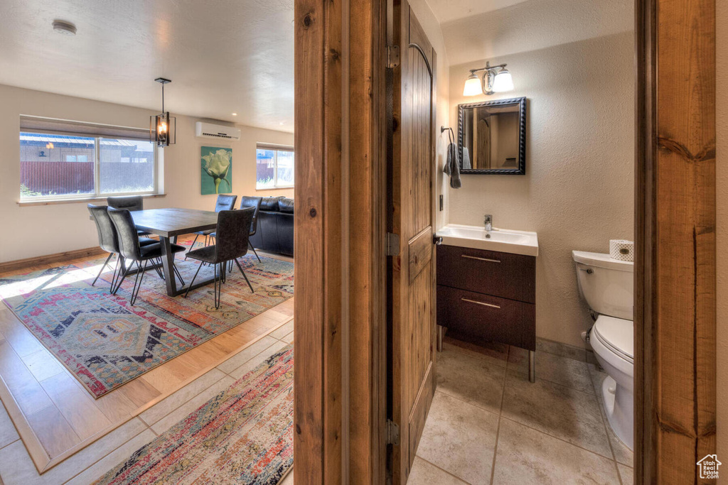 Bathroom featuring a wall mounted air conditioner, hardwood / wood-style flooring, vanity, and toilet