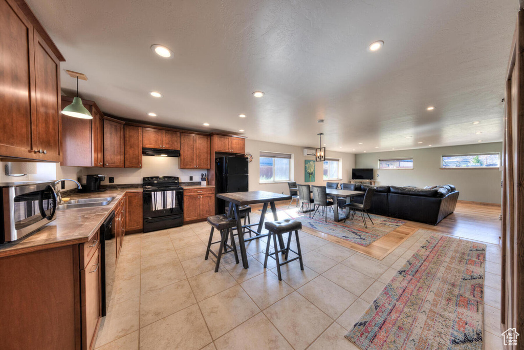 Kitchen featuring black appliances, plenty of natural light, decorative light fixtures, and sink