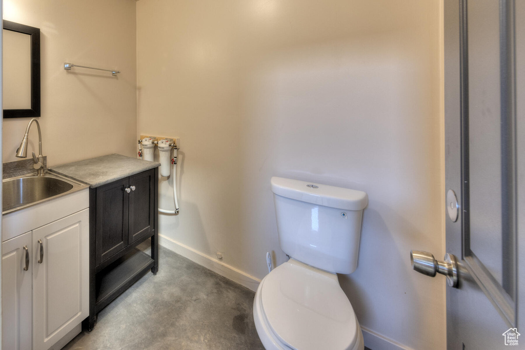 Bathroom with vanity, toilet, and concrete flooring