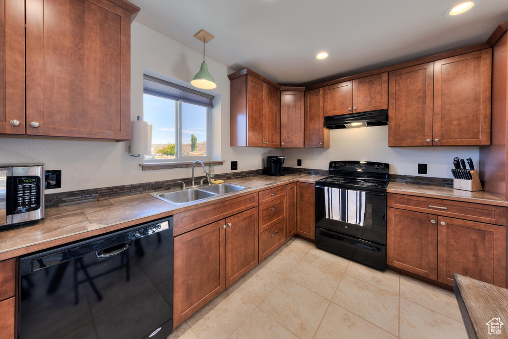 Kitchen with decorative light fixtures, sink, and black appliances