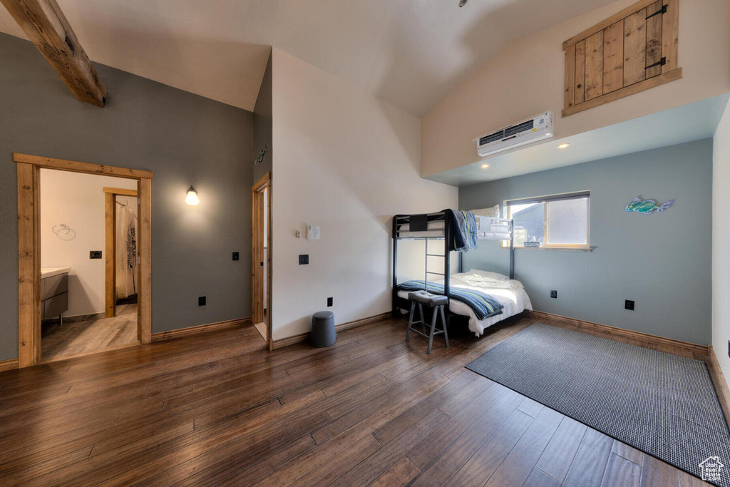 Bedroom with an AC wall unit, vaulted ceiling with beams, and dark hardwood / wood-style floors