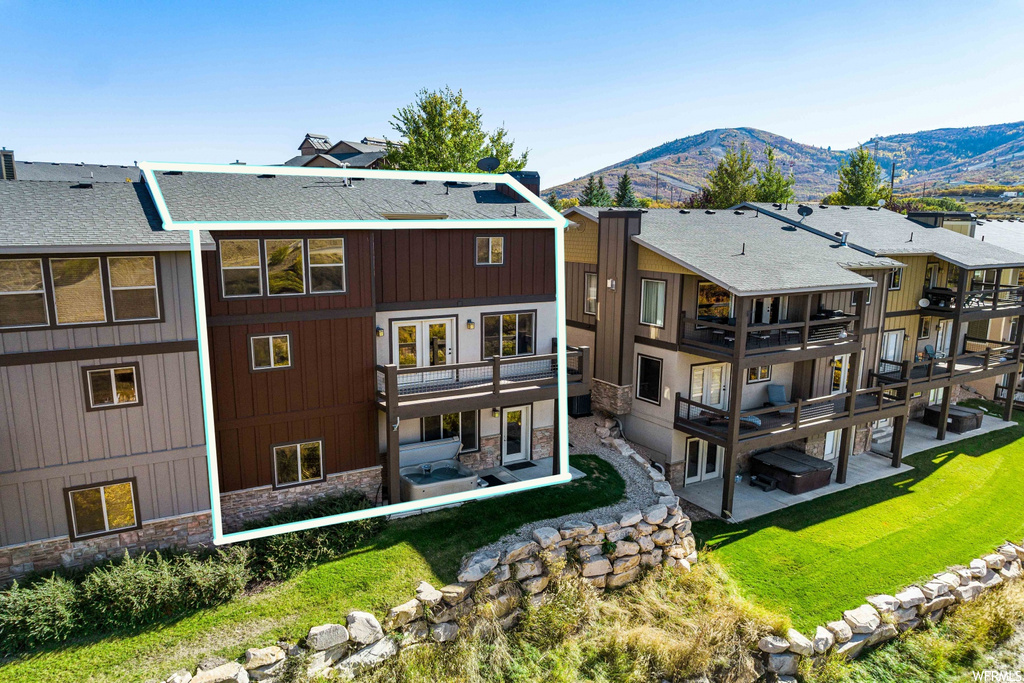 Back of property featuring a yard, balcony, a patio area, and a mountain view